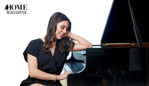 Woman in black smiling and laying arm on piano