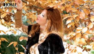 Woman in red hair holding brown leaf among trees