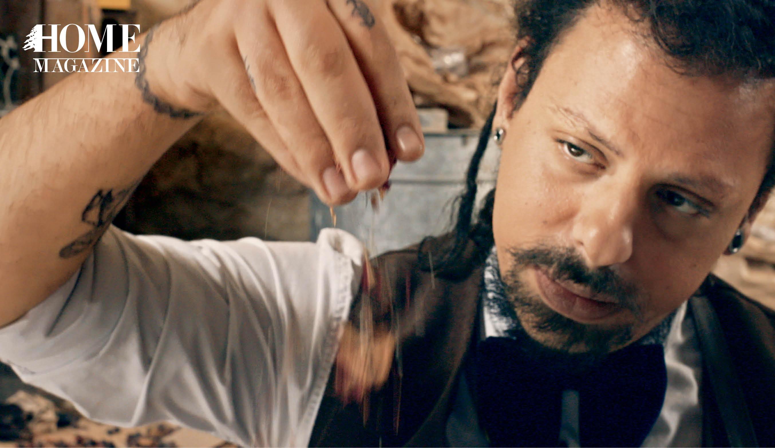 Man with long hair and tattoo on hand sprinkling seeds