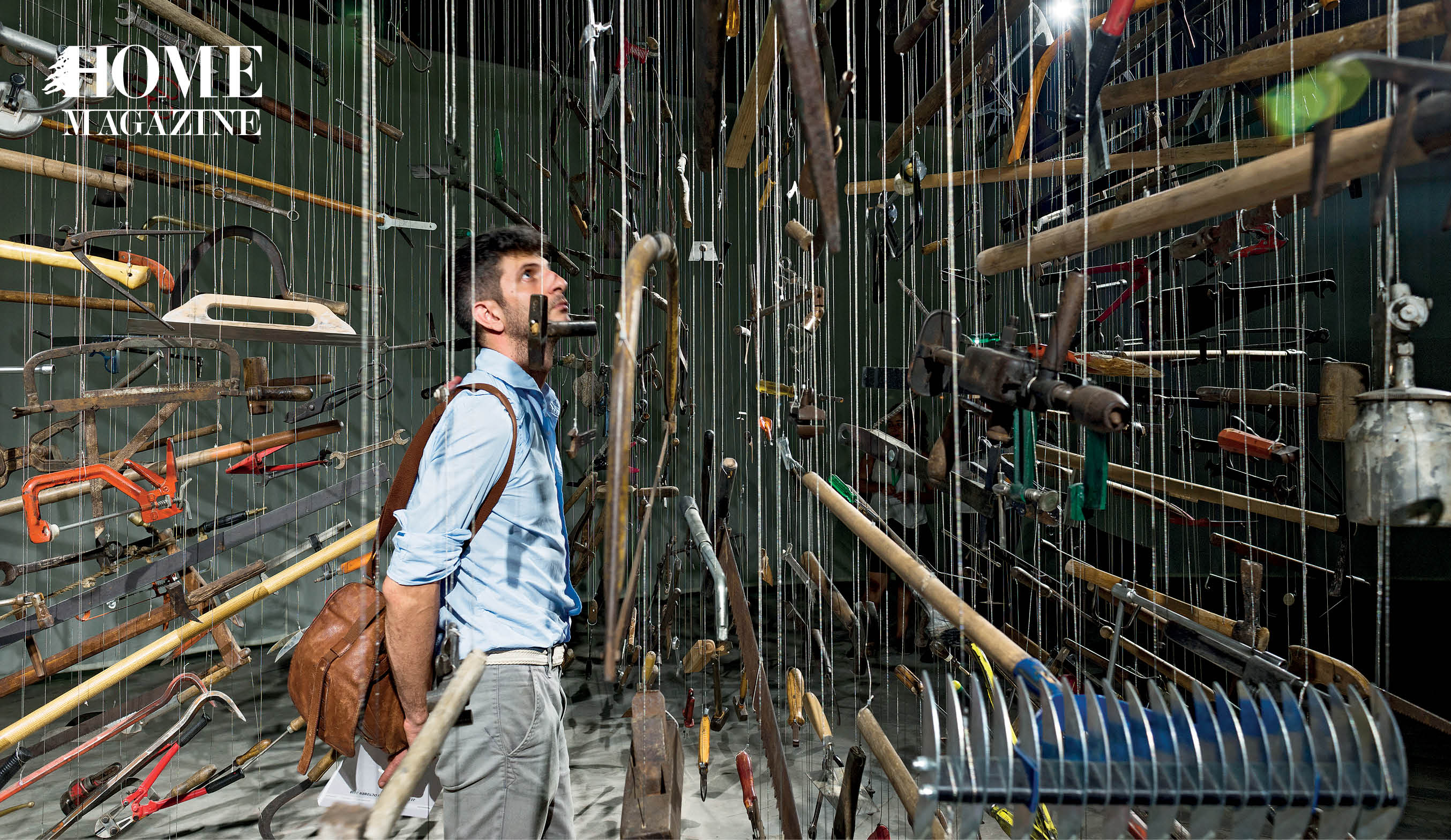 Man looking at metal and wood objects hanging from ceiling