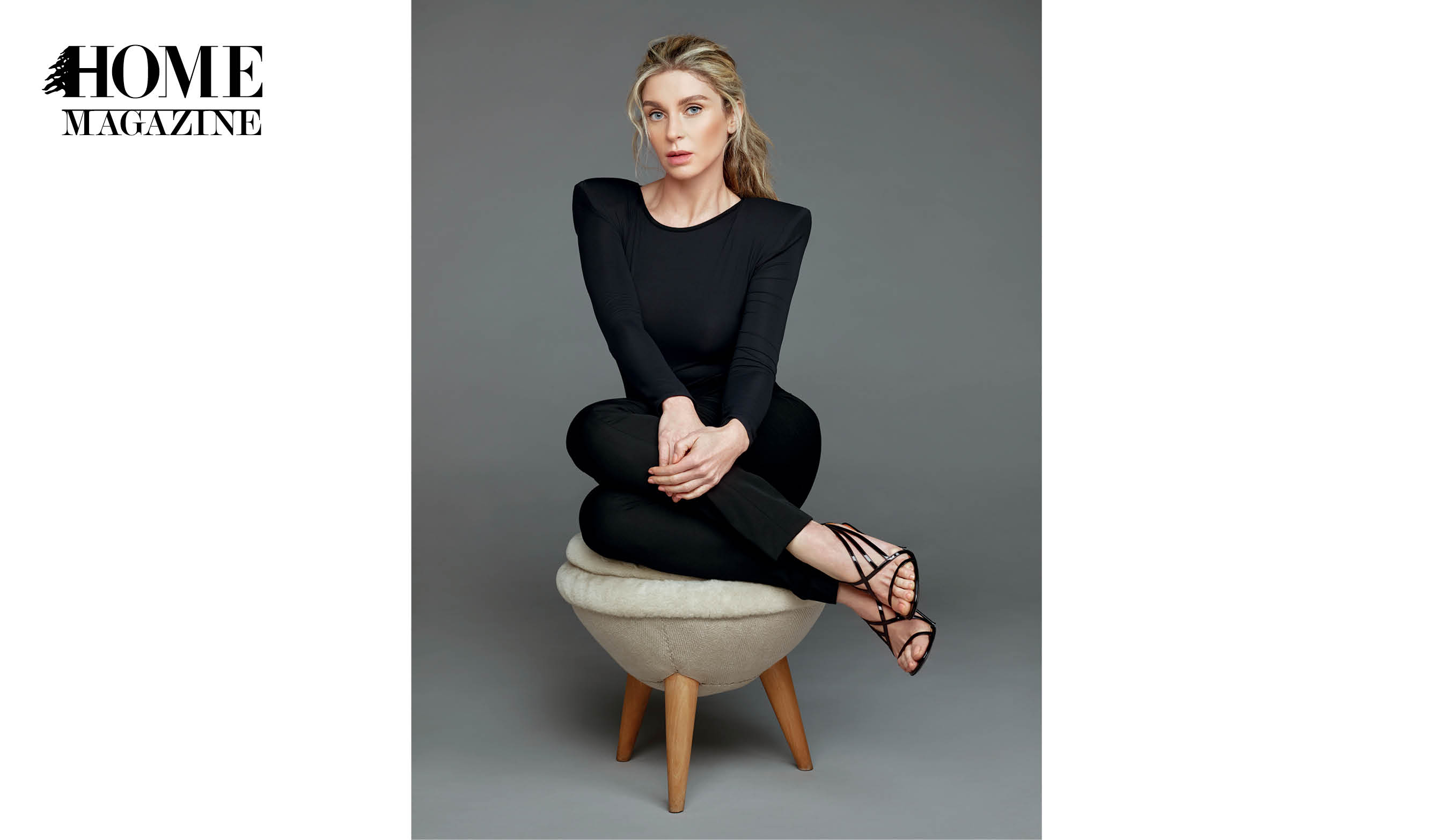Blond woman in black attire and sandals sitting on a pouf chair