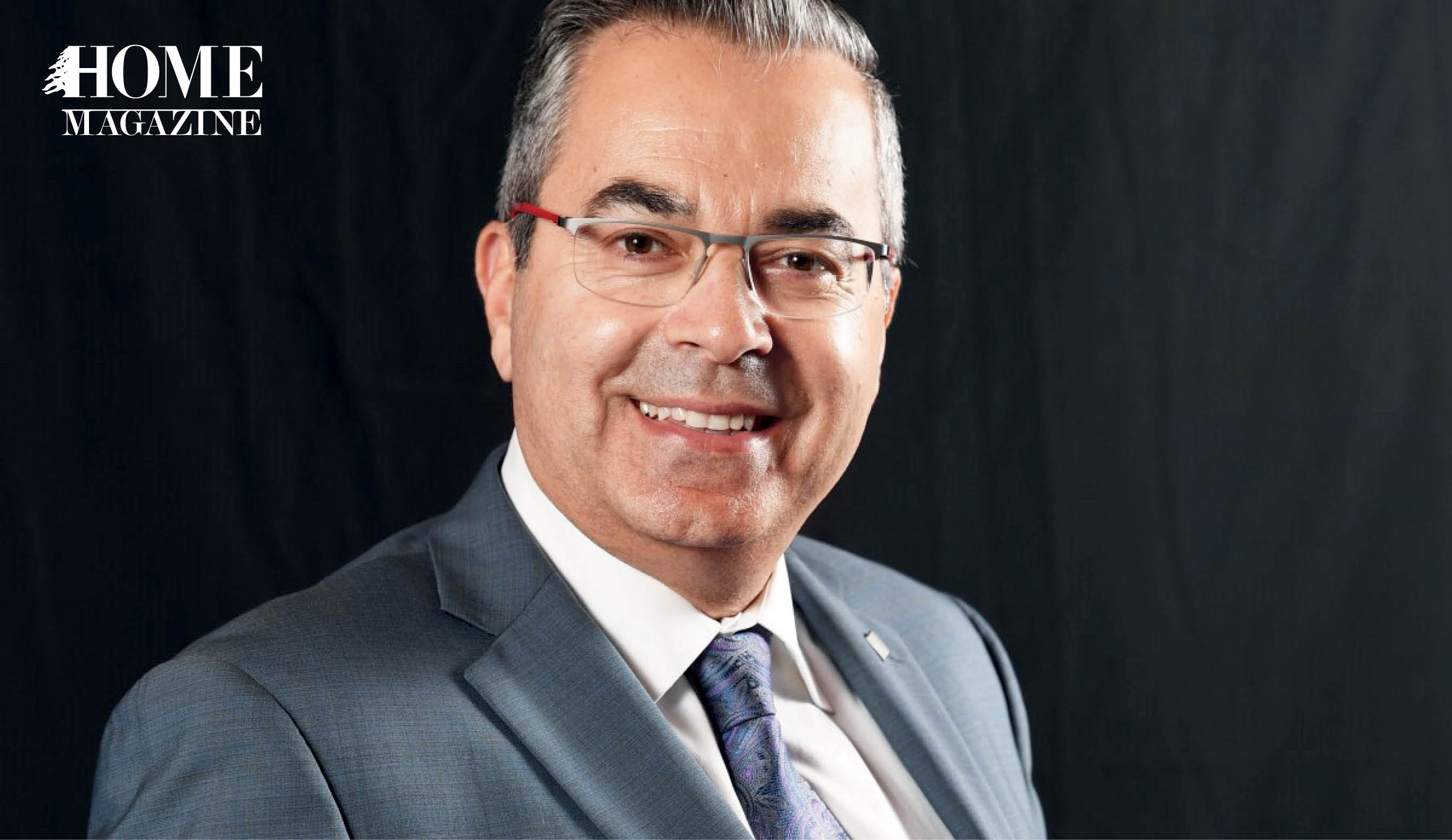 Man smiling in grey suit and wearing eyeglasses