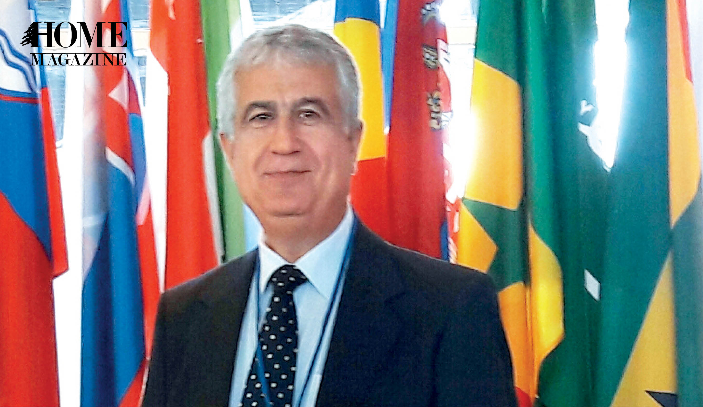 Man in suit standing in front of colored flags