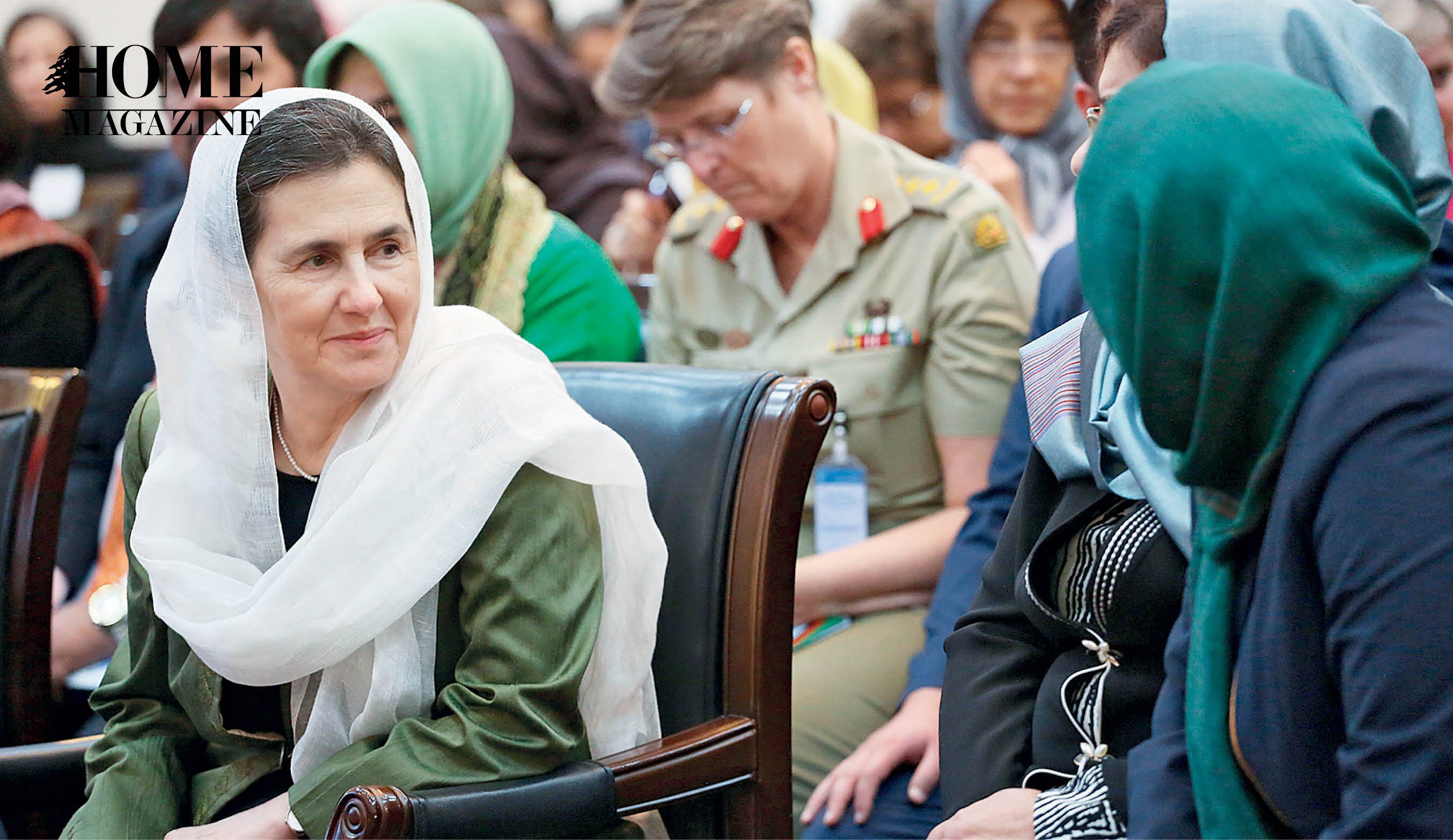 Old woman with white veil next to a woman with green veil on head among a crowd of seated people