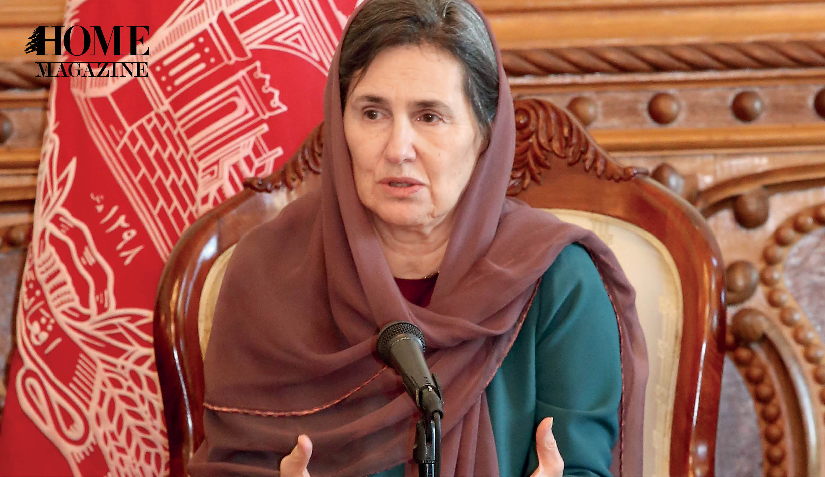 Old woman with brown veil speaking on a microphone with red flag in background