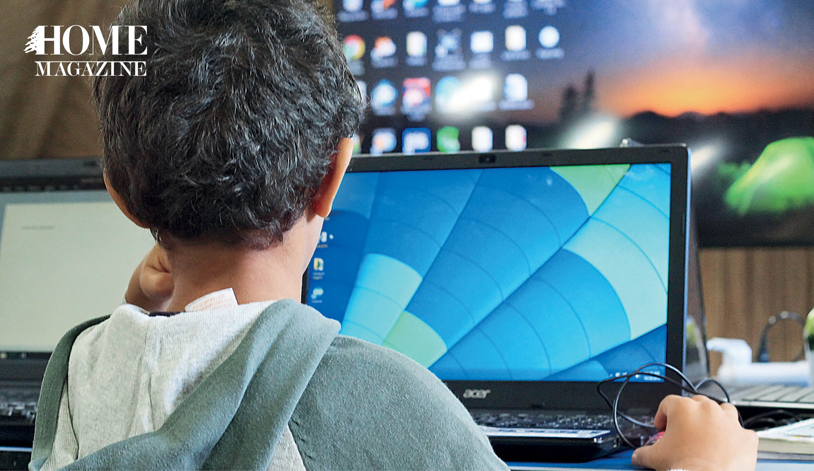 Back profile of a boy sitting in front of a laptop