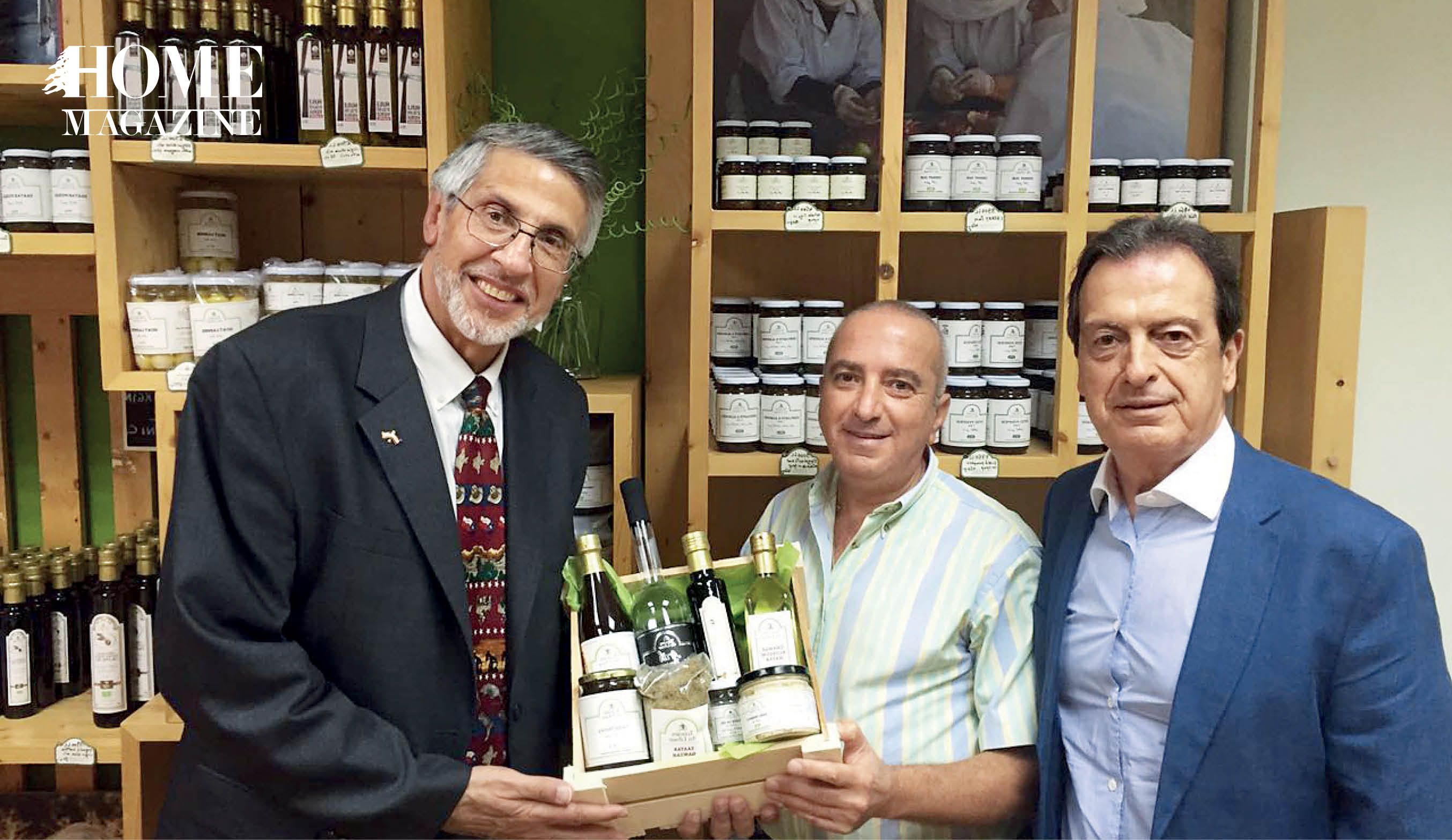 Three men with two of them holding a box of bottles and jars