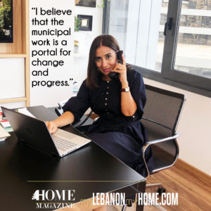 Woman in black dress sitting on a chair with laptop in office setting