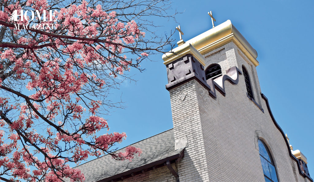 Church with blue sky in background and a tree of pink flowers