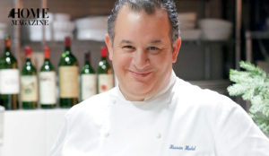 A smiling man wearing a white coat