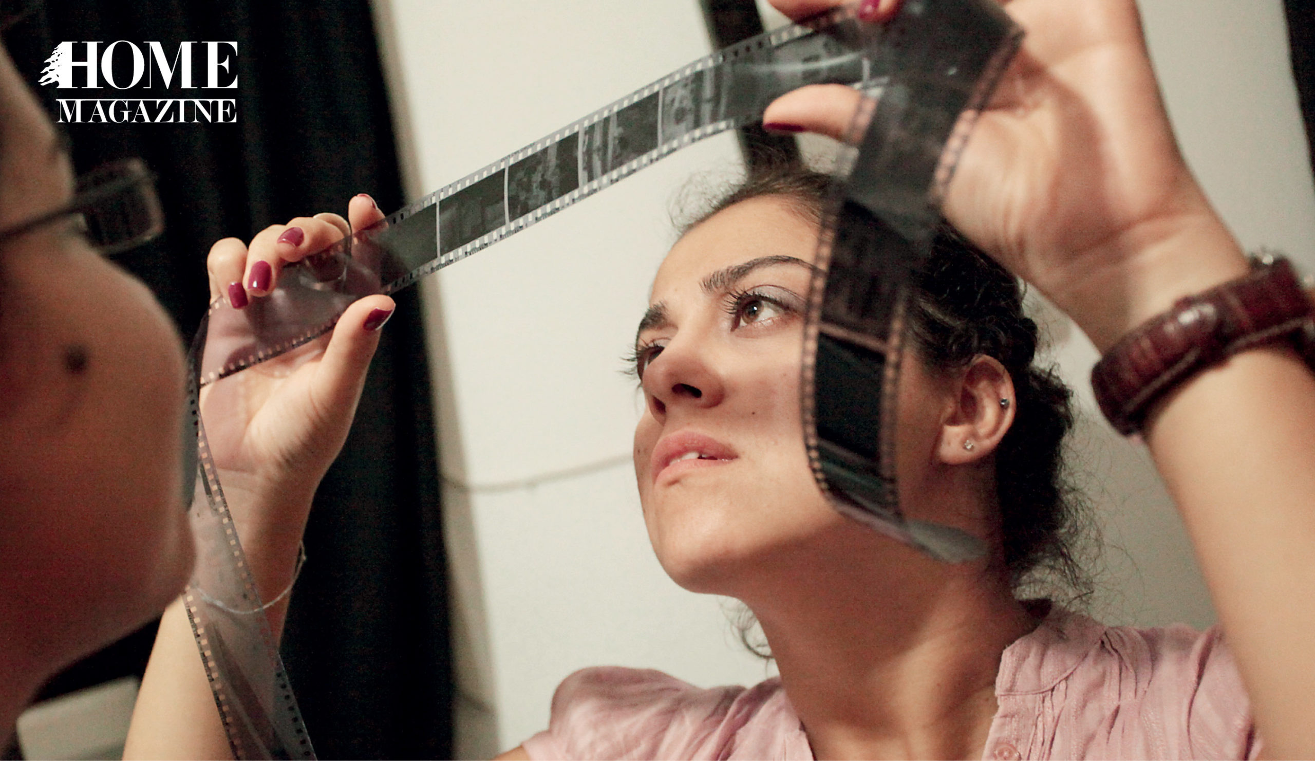 A woman looking through a camera's black film tape