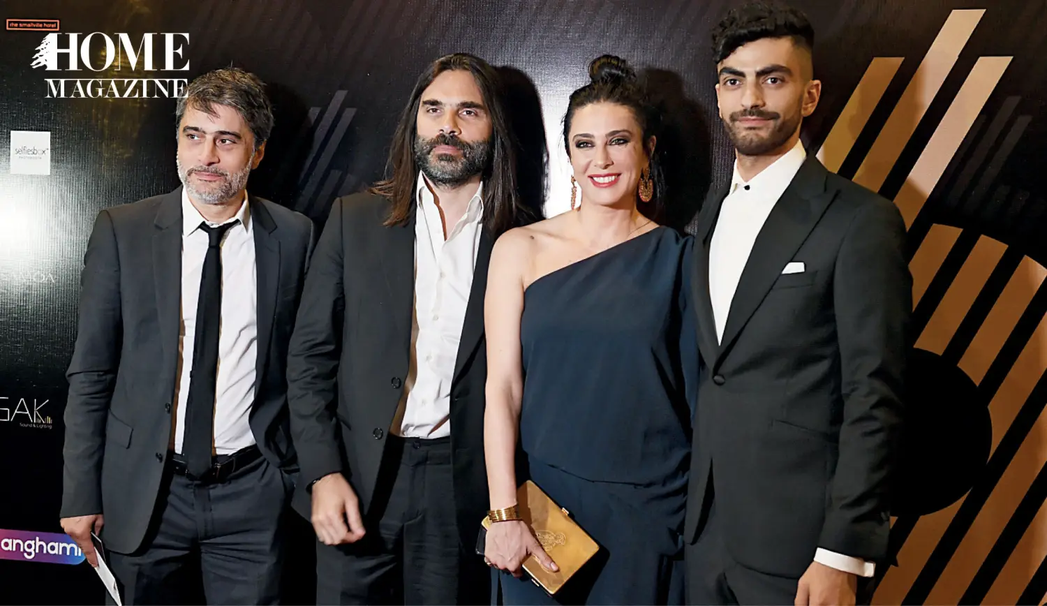 Three smiling men in black suits and a woman in a black dress