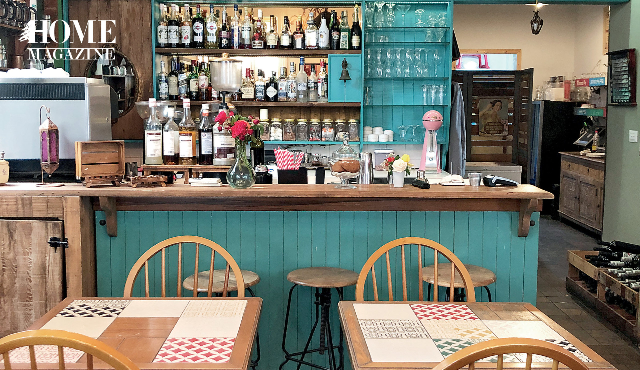 Blue bar with glasses and bottles and wooden chairs and tables
