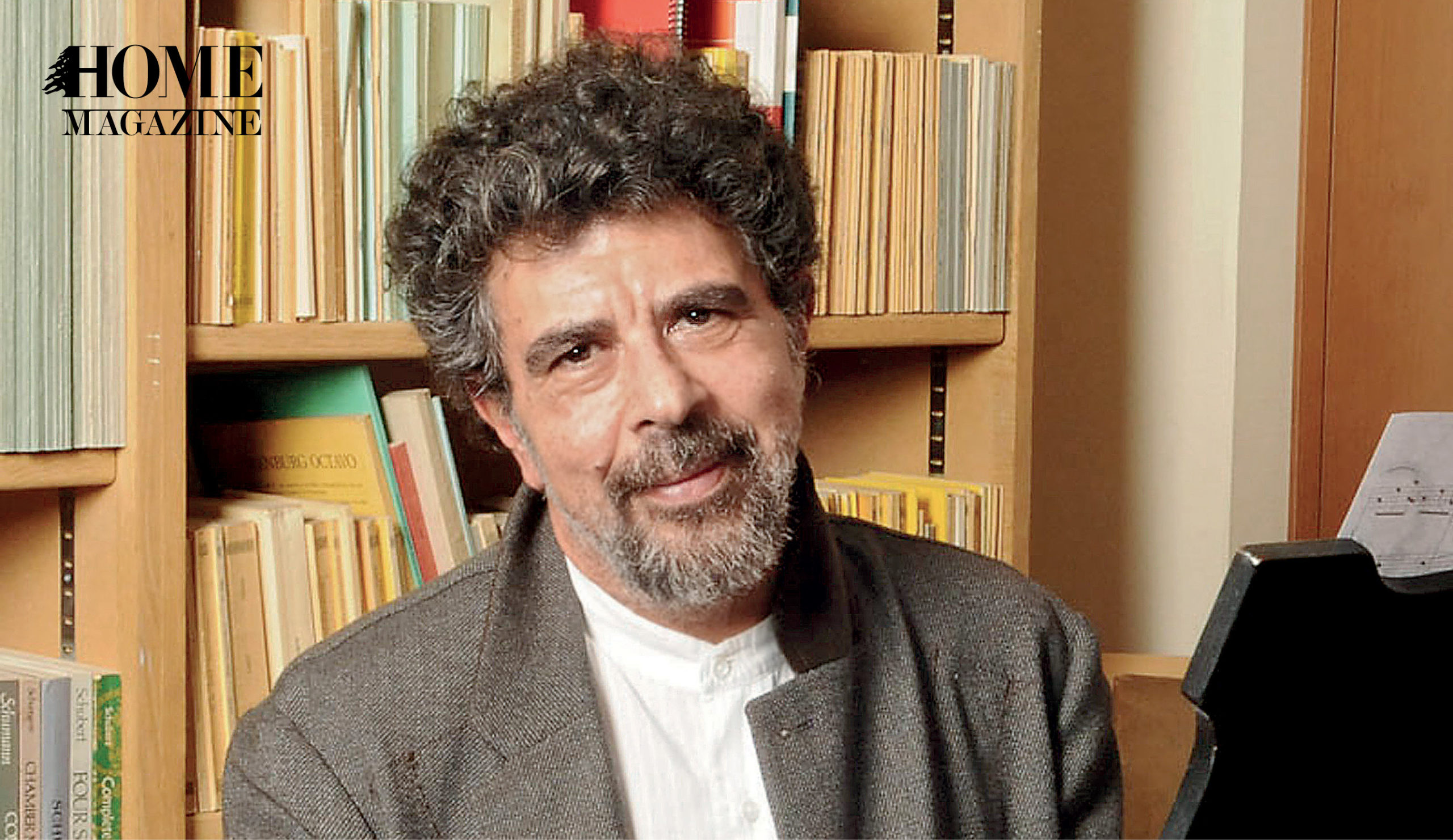 Portrait of a man with curly hair and beard and background of books on shelves