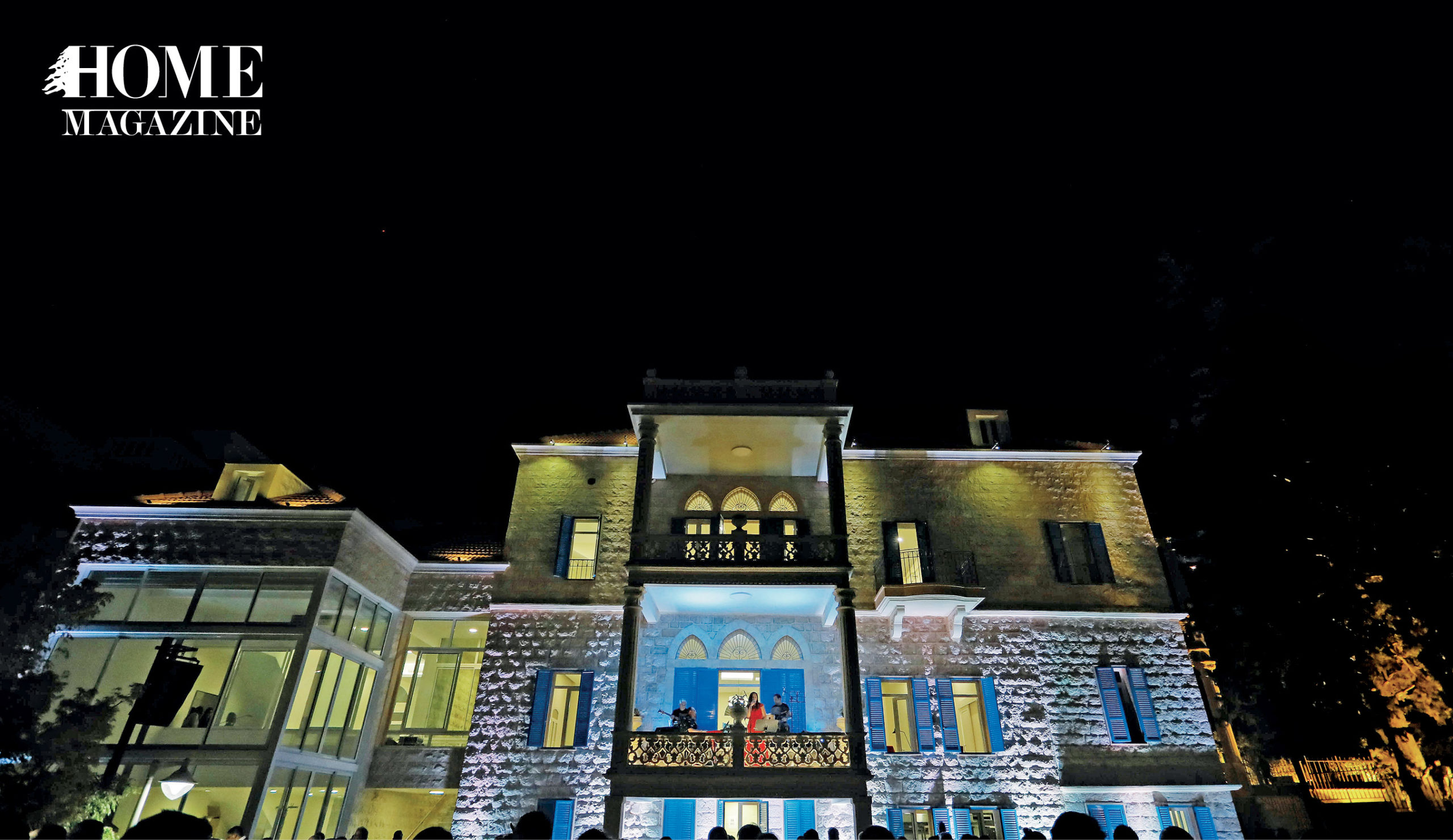 Woman in red dress and band performing on balcony of a house at night with crowd and lighting