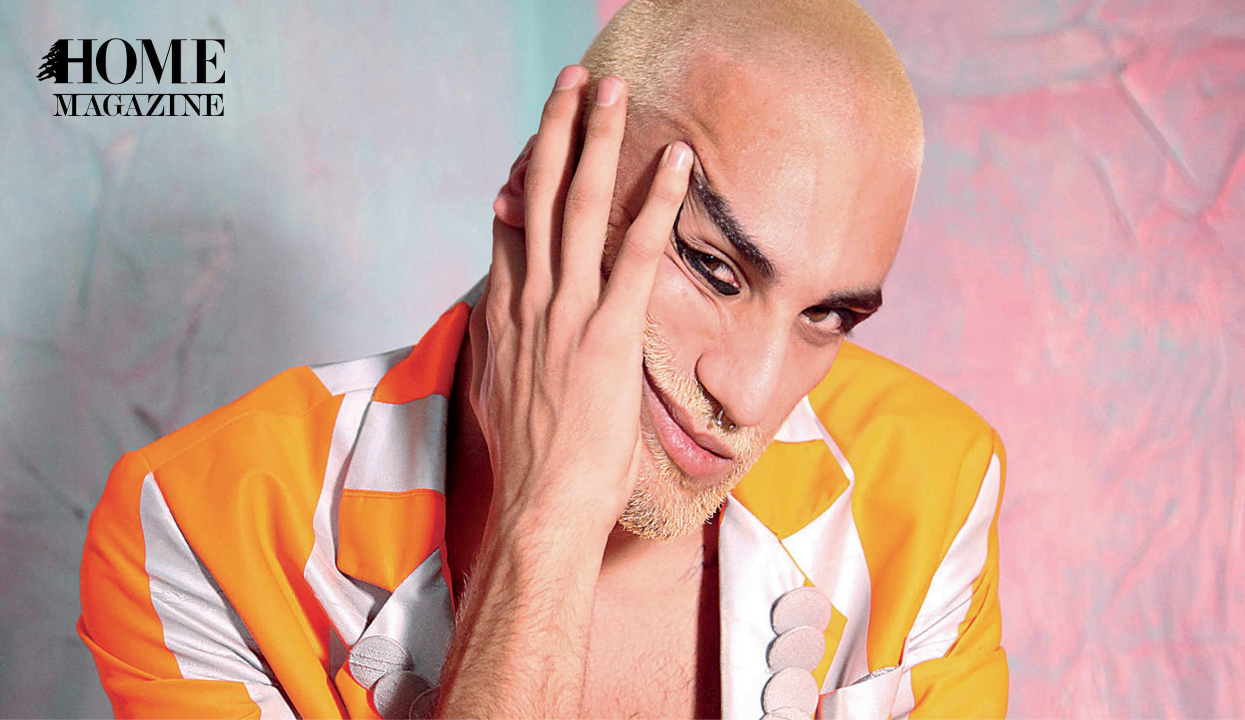 Face portrait of a bold man with an orange colored shirt with his hand on his face
